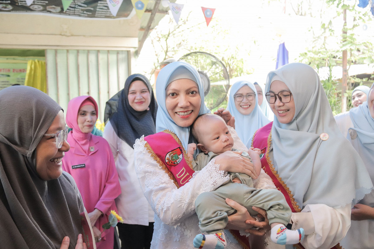 Bunda PAUD Kota Pekanbaru Sulastri menggendong bayi saat melakukan kunjungan ke Puskesmas Kecamatan Limapuluh, Rabu (11/6/2025).