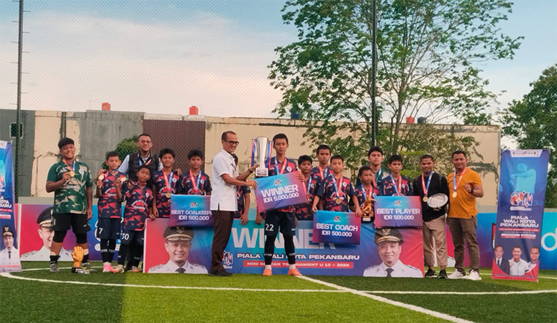 Ketua Askot PSSI Pekanbaru Roni Saputra menyerahkan trofi juara kepada perwakilan Wahana SS U-13 di Benecia Arena Pekanbaru, Selasa (17/6/2025).