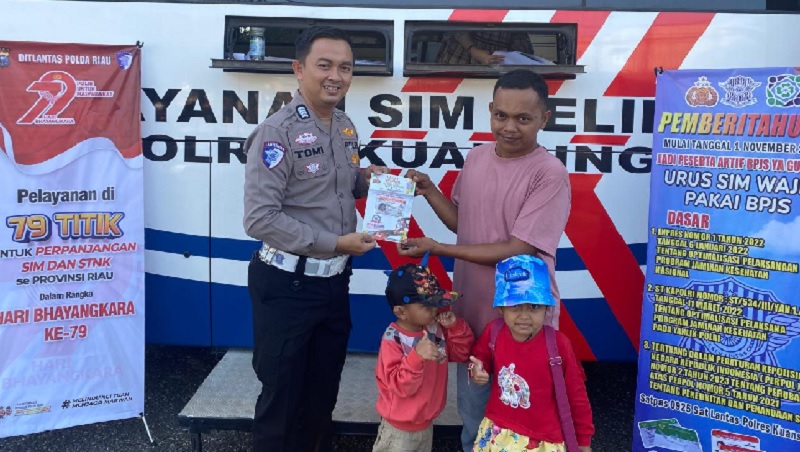 Personel Satlantas Polres Kuansing menyerahkan SIM pada masyarakat yang memanfaatkan SIM keliling menyambut Hari Bhayangkara ke 79 tahun, Ahad (22/6/2025) di Kawasan Limuno TelukkKuantan.