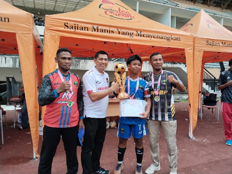 Ketua Fossbolindo Riau Zepron (dua kiri) menyerahkan trofi juara kepada  kapten SSB Putra Muda di Stadion Utama Riau, Pekanbaru, Ahad (22/6/2025).