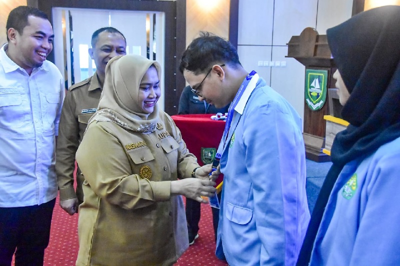 Bupati Bengkalis Kasmarni mengalungkan tanda peserta Kukerta Unri di Ruang Dang Merdu, Lantai IV Kantor Bupati, Bengkalis, Selasa (24/6/2025).