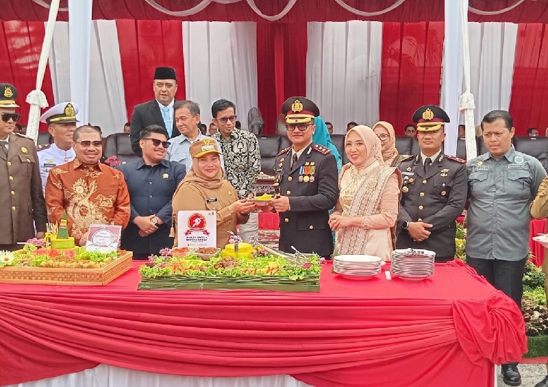 Bupati Bengkalis Kasmarni menyerahkan tumpeng kepada Kapolres Bengkalis AKBP Budi Setiawan dalam peringatan Hari Bhayangkara ke-79 di Halaman Polsek Mandau, Selasa (1/7/2025).