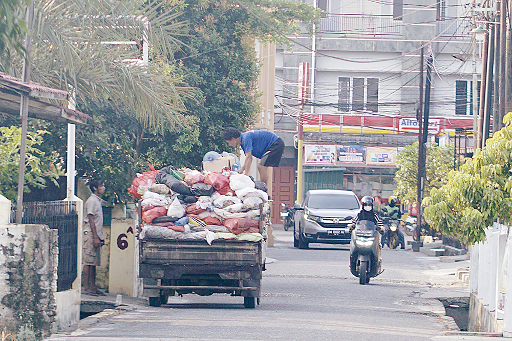MHD AKHWAN/RIAU POS ANGKUT SAMPAH: Menggunakan mobil bak terbuka, pekerja mengangkut sampah dari rumah warga di Jalan Durian, Selasa (1/7/2025).
