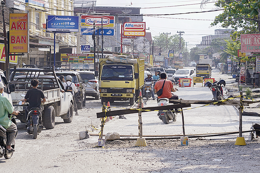MHD AKHWAN/RIAU POS PERBAIKAN JALAN: Pengendara melintas di Jalan Dharma Bakti, Kecamatan Payung Sekaki yang tengah diperbaiki dengan sisrem rigid (betonisasi), Senin (30/6/2025).