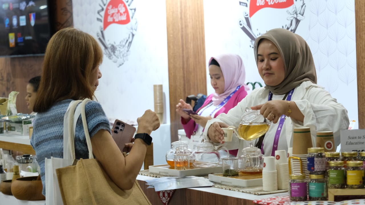 Pelaku UMKM asal Bogor tengah memperkenalkan produk teh racikannya kepada pengunjung dalam ajang pameran internasional. Dukungan BRI melalui pembinaan dan akses pembiayaan membantu UMKM ini menembus p