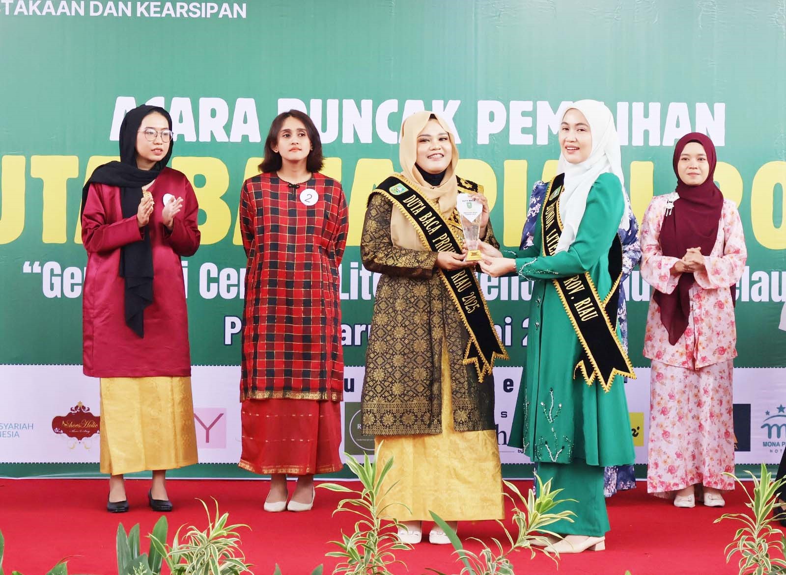 Bunda Literasi Riau, Henny Sasmita Wahid (dua kanan), menyerahkan trofi pemenang Duta Baca Riau 2025-2029 kepada Wahyu Oktafialni di Perpustakaan Soeman Hs, Pekanbaru, Senin (30/6/2025).