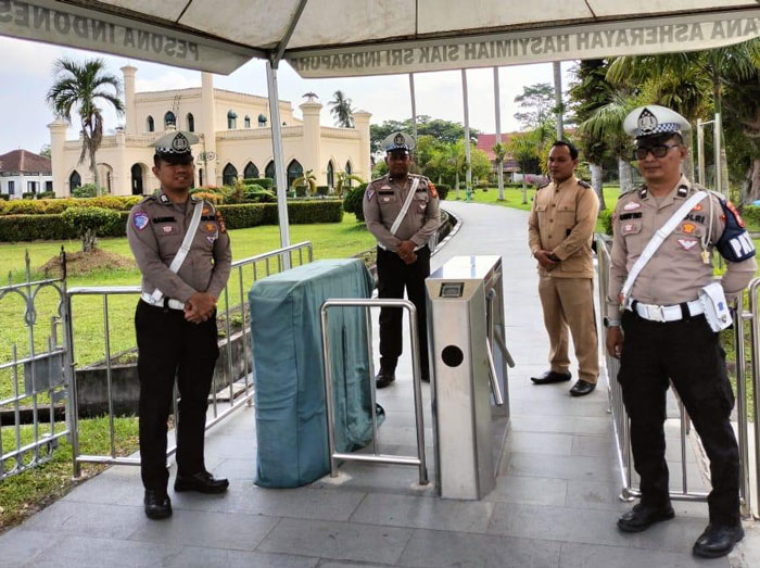 Personel Polres Siak melakukan patroli dengan berdiri di gerbang Istana Asserayah Alhasyimiah Kota Siak, Ahad (6/7/2025).