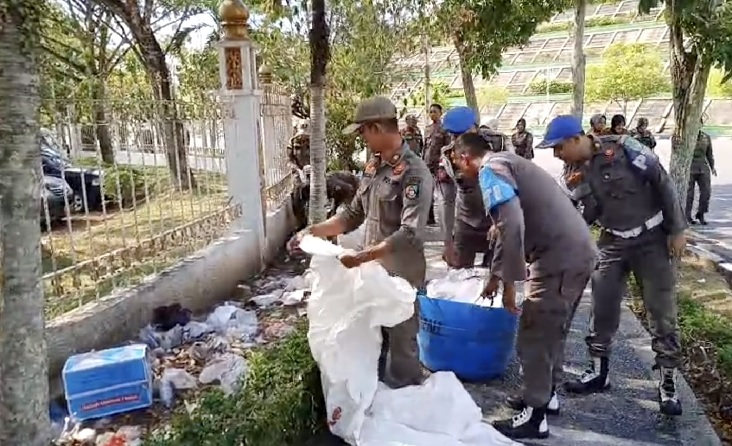 Puluhan personel Satpol PP Rohul diturunkan untuk membersihkan tumpukan sampah yang berserakan di luar pagar Kantor Bupati Rohul, Senin (7/7/2025).