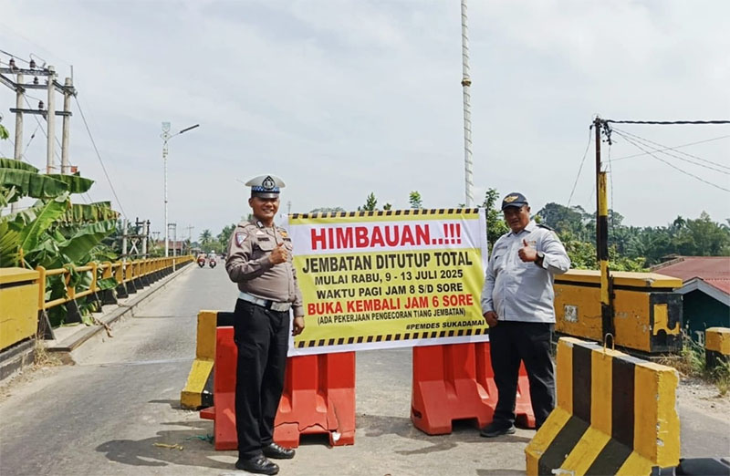 Personel kepolisian dan Dishub Rohul memasang baliho imbauan penutupan total jembatan Sungai Rokan di Kecamatan Ujung Batu, Selasa (8/7/2025).