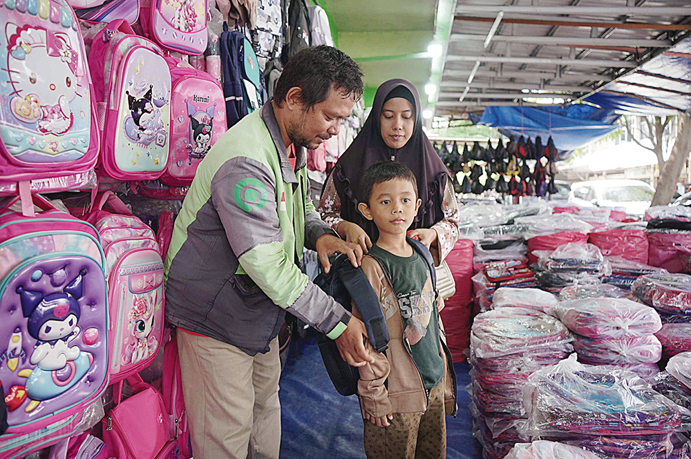 Dibantu orang tua, seorang anak mencoba tas sekolah baru yang dijual di salah satu toko di Jalan Ahmad Yani, Pekanbaru, Rabu (9/7/2025).