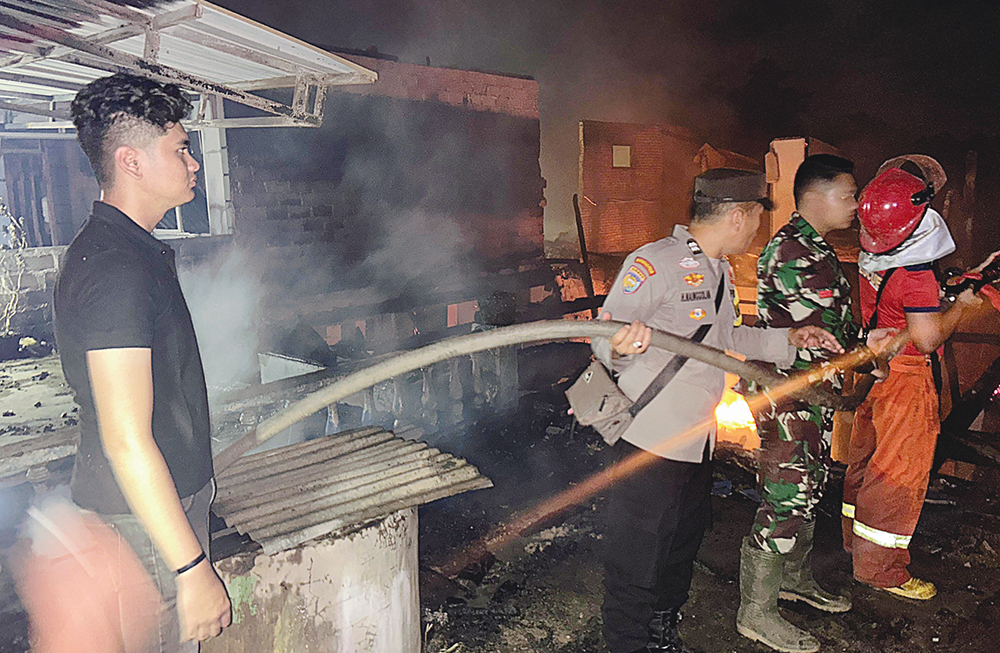 Personel Polsek Pasir Penyu bersama tim dan warga ikut melakukan pemadaman api yang meng&shy;hanguskan enam unit rumah di Kelurahan Air Molek, Selasa (8/7/2025) malam.