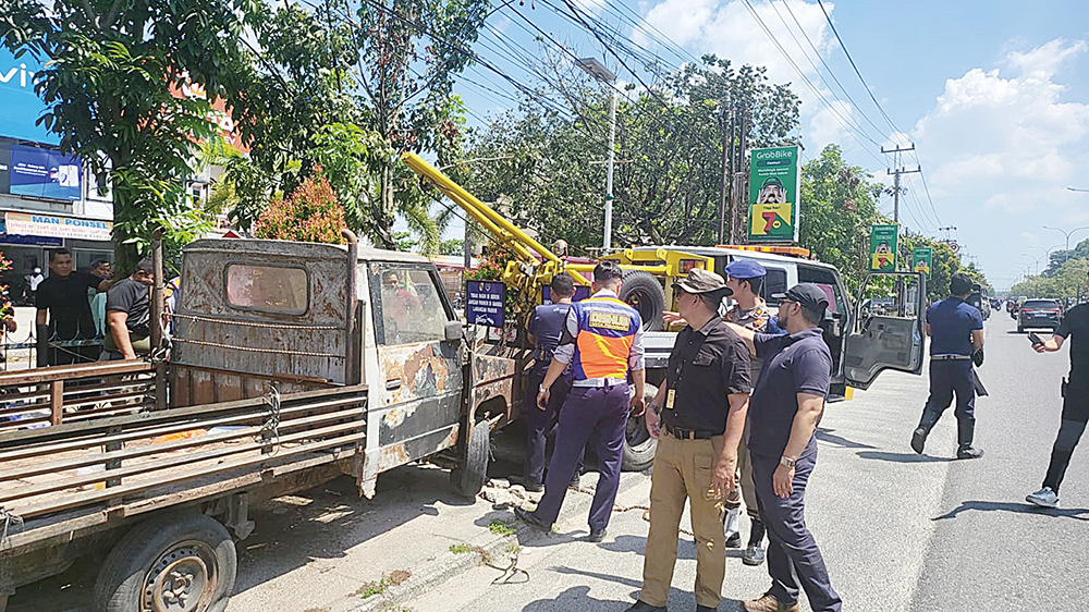 Petugas Satpol PP Kota Pekanbaru menderek mobil yang dipakai untuk berjualan  (&rdquo;lapak berjalan&rdquo;) di pinggir Jalan HR Soebrantas saat penertiban PKL, Kamis (10/7/2025) pagi,