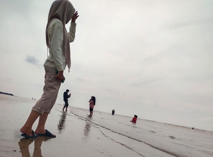 Pengunjung pantai bermain air laut di Pantai Indah Selatbaru Kecamatan Bantan Bengkalis, Ahad (13/7/2025).