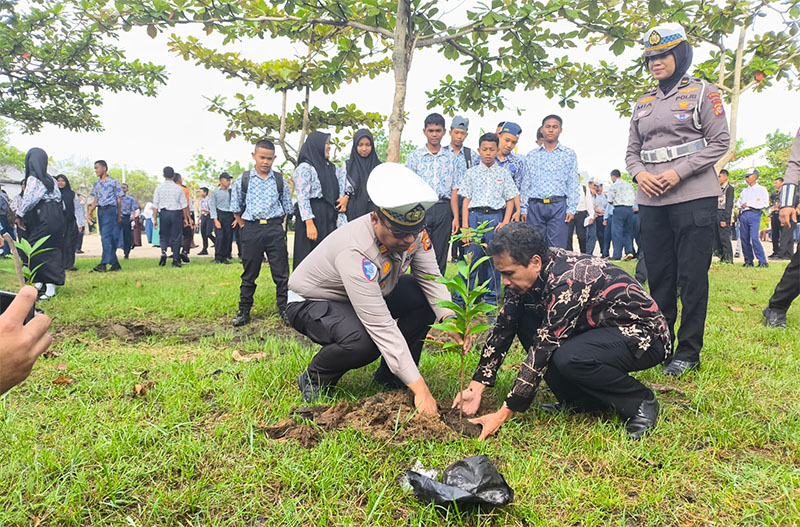 Kasat Lantas Polres Inhil AKP Fandri dan Kepala SMKN 2 Tembilahan, Hasmar, menanam bibit pohon di lingkungan sekolah.