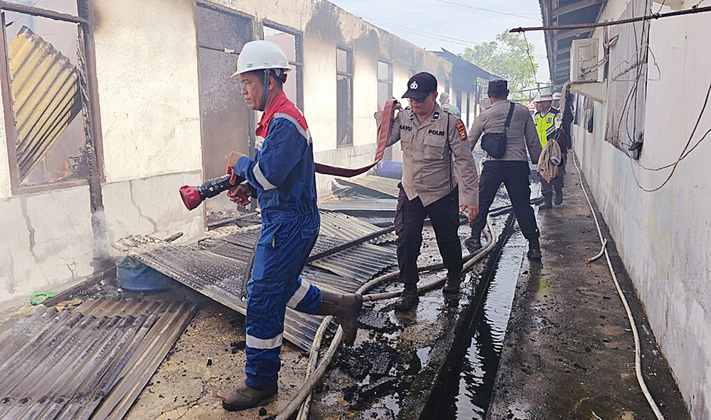 Petugas pemadam kebakaran dan kepolisian melakukan pemadaman api yang membakar asrama SMK Teknologi YPL Lirik, Kabupaten Inhu, Kamis (17/7/2025).