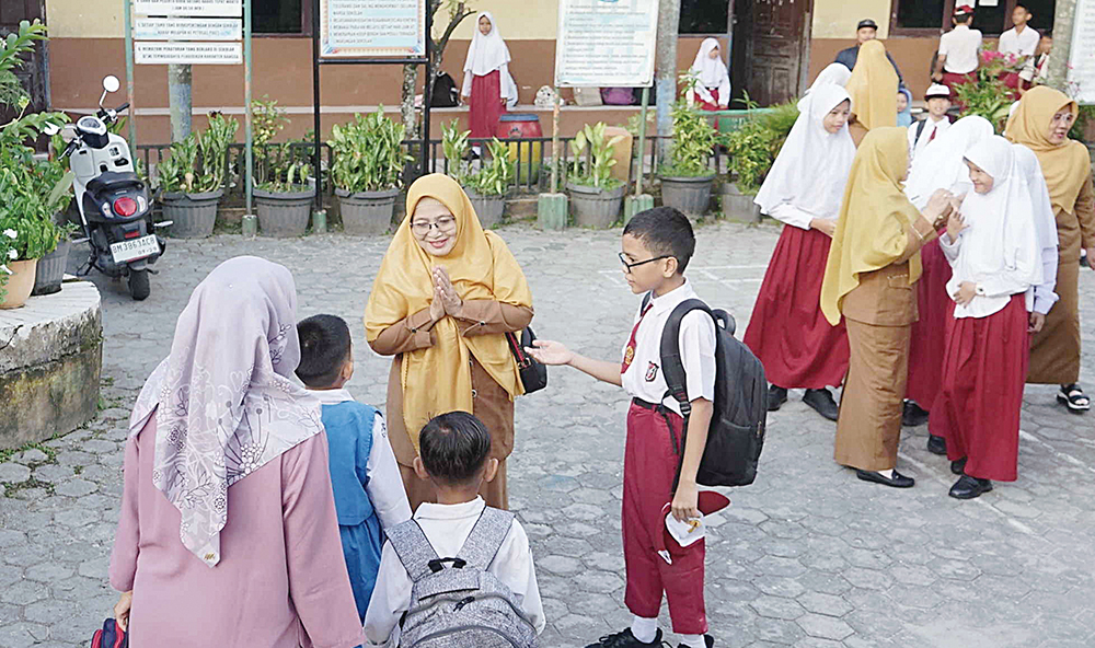 Sejumlah guru menyambut murid yang baru masuk sekolah di SDN 165 Jalan Serasi Pekanbaru, Senin (14/7/2025).