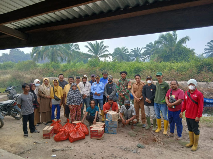 Pj Penghulu Rantau Panjang Kiri, Jefrianto dan tim gabungan bersama dengan warga yang mengungsi karena dampak kabut asap di Dusun Mekar Jaya di sela penyerahan bantuan, Senin (21/7/2025).