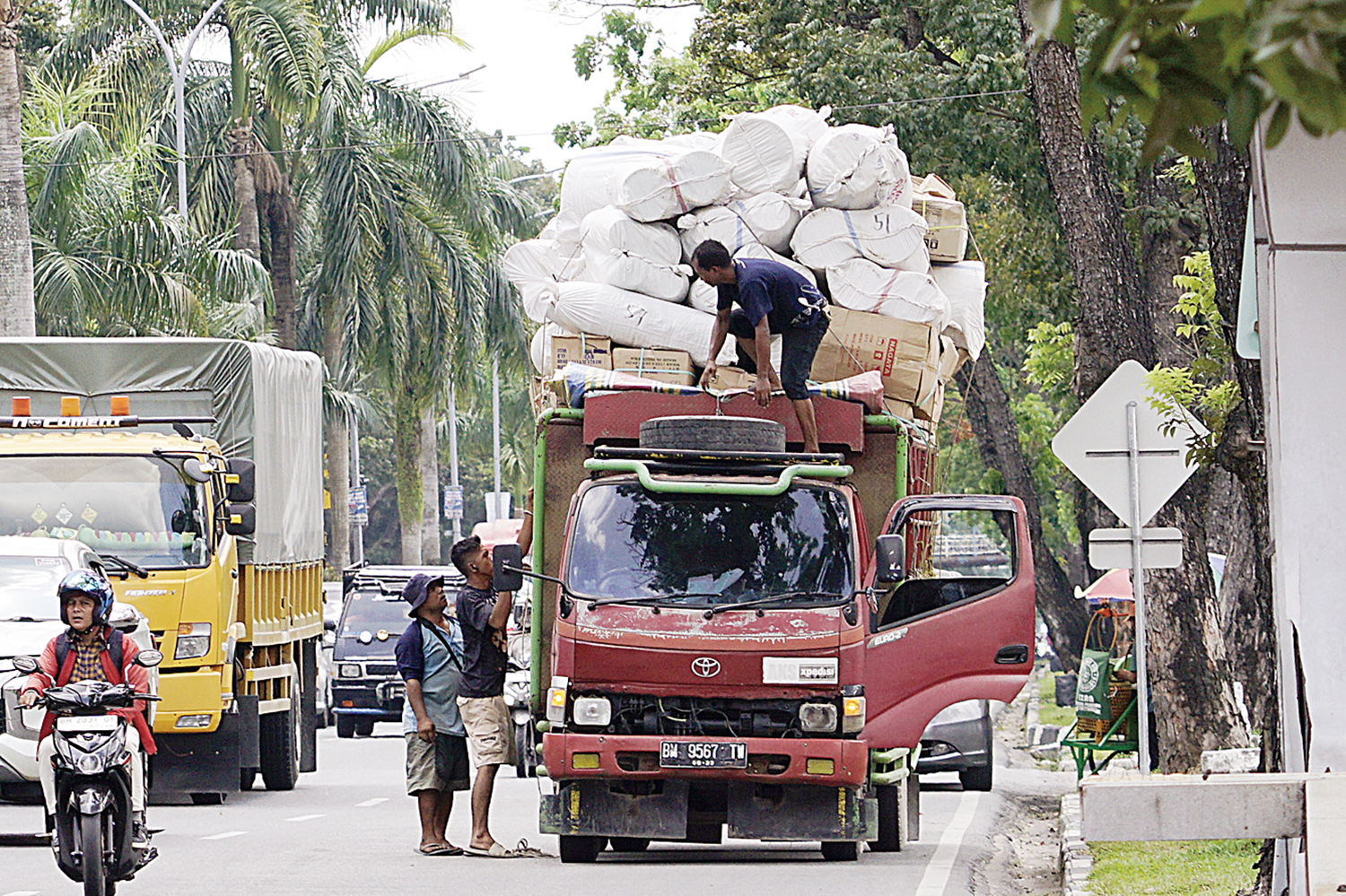 Sopir dan kernet memperbaiki muatan yang kelebihan saat melintas di Jalan Jenderal Sudirman, Pekanbaru,  Senin (21/7/2025). Truk angkutan Over Dimension Over Loading dilarang melintas di dalam Kota Pekanbaru mulai 1 Agustus 2025.