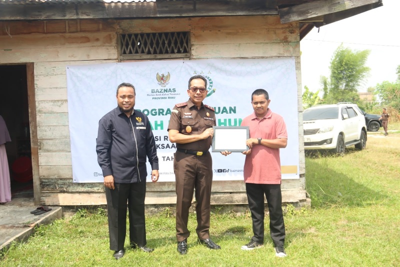 Kajati Riau Akmal Abbas, didampingi Ketua Baznas Provinsi Riau Masriadi Hasan, menyerahkan secara simbolia bantuan Rumah Layak Huni kepada salah seorang pegawai Non-ASN Kejati Riau.