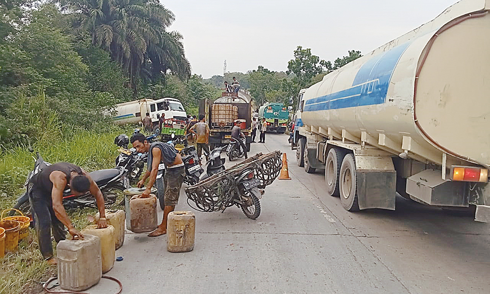 Masyarakat mengambil tumpahan CPO dari truk tangki yang mati mesin di dekat Kantor Lurah Bagan Besar, Kota Dumai, Selasa (22/7/2025).