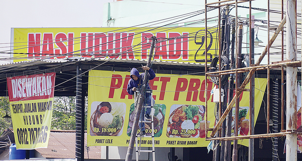 Pekerja memasang jaringan kabel optik di Persimpangan Empat Pasar Pagi Arengka yang semraut, Pekanbaru, Senin (21/7/2025).