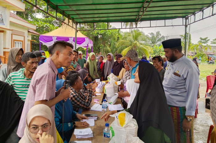Camat Bangko Aspri Mulya melihat proses penyaluran bantuan pangan beras di halaman kantor Camat Bangko, Jumat (25/7/2025).
