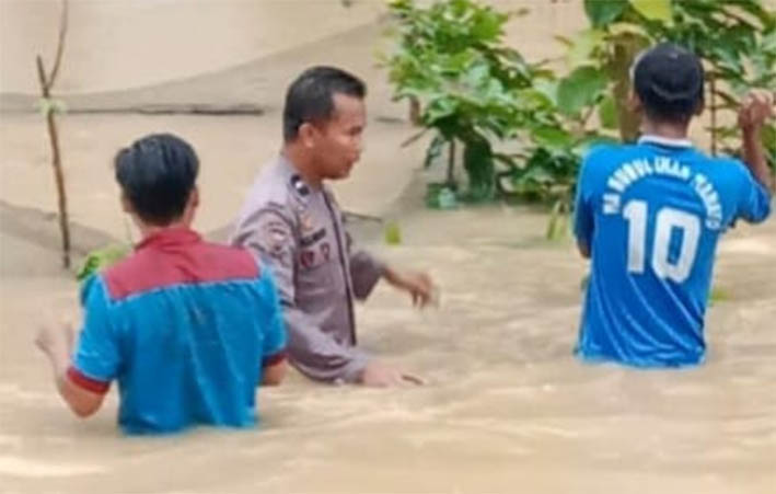 Bhabinkamtibmas Polsek Batang, Aipda Sulaiman bersama warga berupaya menerobos banjir untuk memastikan kondisi warga, Sabtu (26/7/2025).