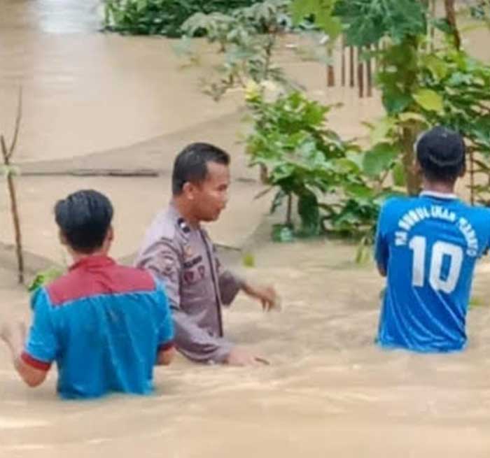 Personel bhabinkamtibmas bersama warga berupaya menerobos banjir untuk mengevakuasi barang warga yang terendam banjir di Dusun I Desa Lahai Kemuning, Kecamatan Batang Cenaku, Kabupaten Indragiri Hulu,