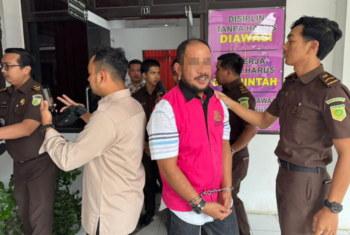 Plt Kepala Desa (Kades) Kelayang berinisial A saat akan digiring ke mobil tahanan untuk dititipkan ke Rutan kelas IIB Rengat, Rabu (30/7/2025).