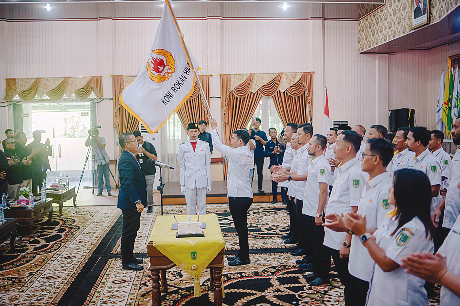 Ketum KONI Rohil Riwansyah mengibarkan bendera organisasi KONI usai dilantik bersama jajaran pengurus KONI Rohil periode 2025-2029 di Bagansiapiapi, Kamis (31/7/2025).