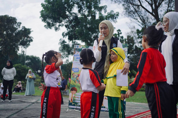 Ketua TP PKK Riau Henny Sasmita Wahid berbincang dengan anak-anak saat kegiatan Pekan Gembira Anak Riau 2025 di halaman kantor gubernur Riau, Ahad (3/8/2025).