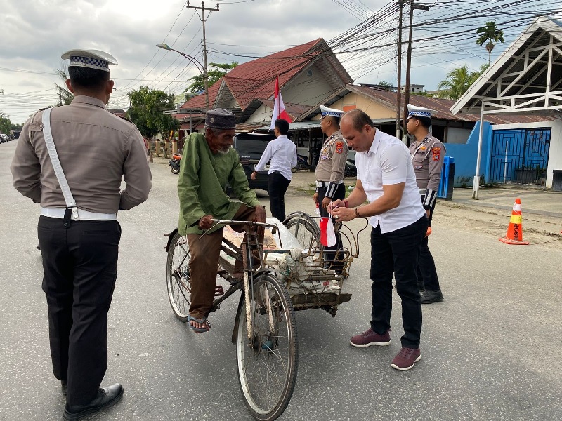 Kasat Intelkam Polres Inhil Iptu Sudarto Sihombing memasangkan bendera merah putih ke becak dayung di Jalan M Boya, Tembilahan, Senin (4/8/2025)