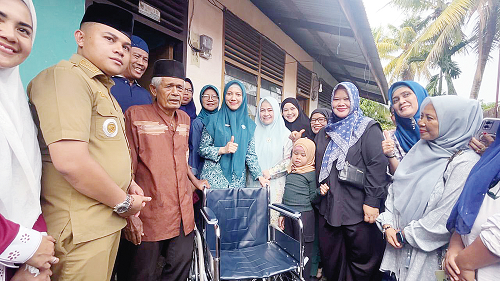 SERAHKAN BANTUAN: Ketua TP PKK Kota Pekanbaru Sulastri Agung (tengah) menyerahkan bantuan kursi roda kepada satu keluarga di Kecamatan Bukit Raya, Selasa (5/8/2025).