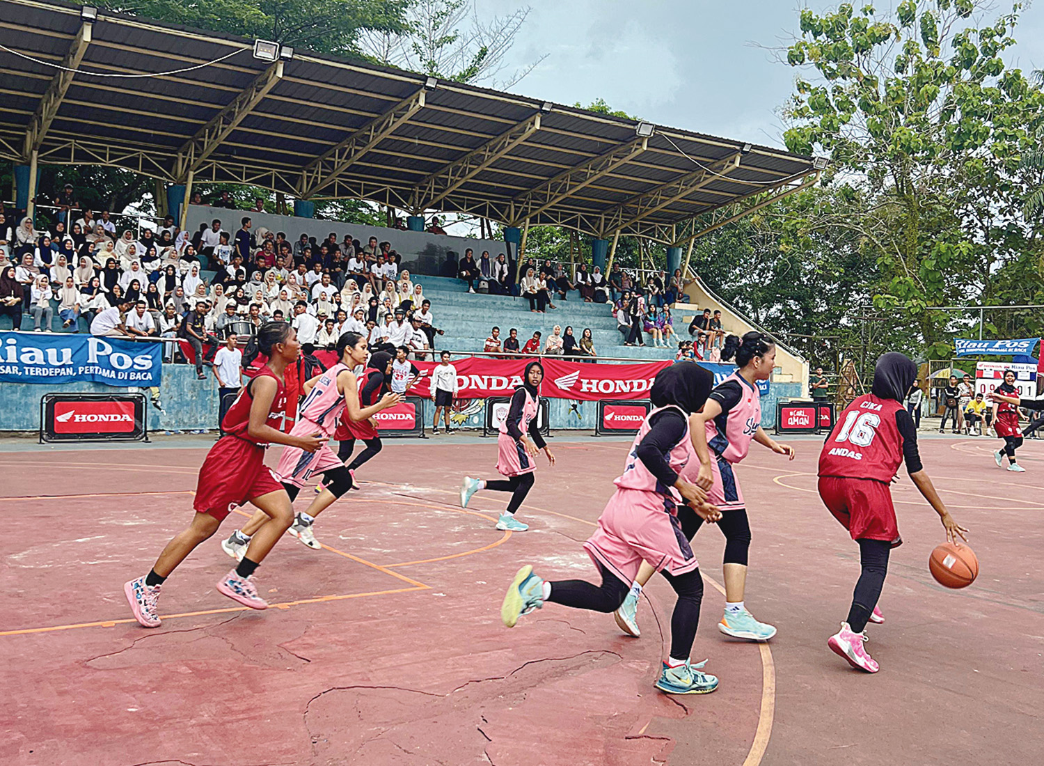Pemain putri SMAN 1 Seberida (merah) mendribel bola dan dikejar pemain SMAN 2 Rengat pada laga Riau Pos-HSBL Seri Rengat di Lapangan Perbasi Rengat, Kamis (7/8/2025).