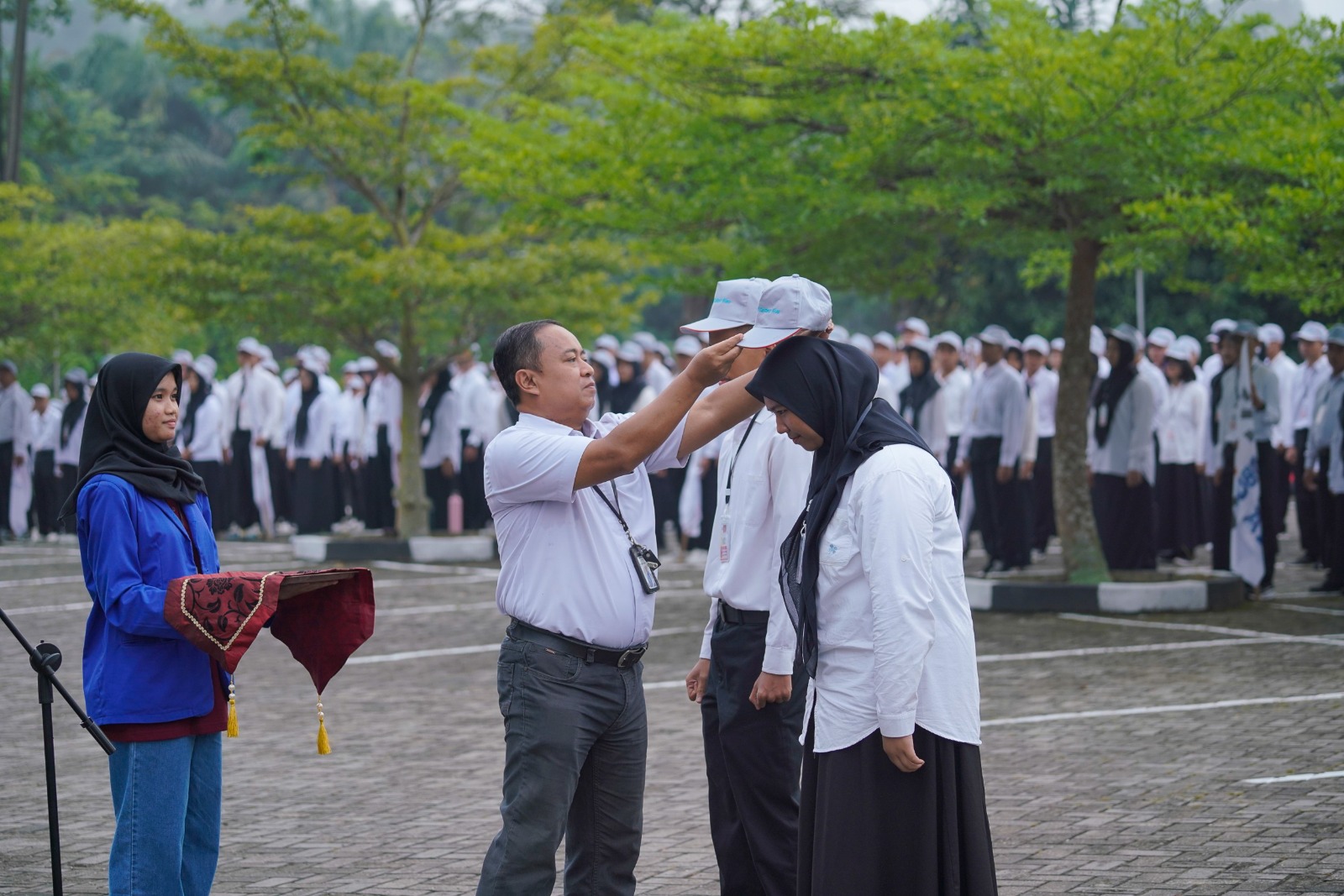 Direktur PCR, Dr. Dadang Syarif Sihabudin, S.Si M.Sc memasangkan atribut ISO kepada perwakilan mahasiswa baru di halaman kampus pada hari Senin (11/8/2025).