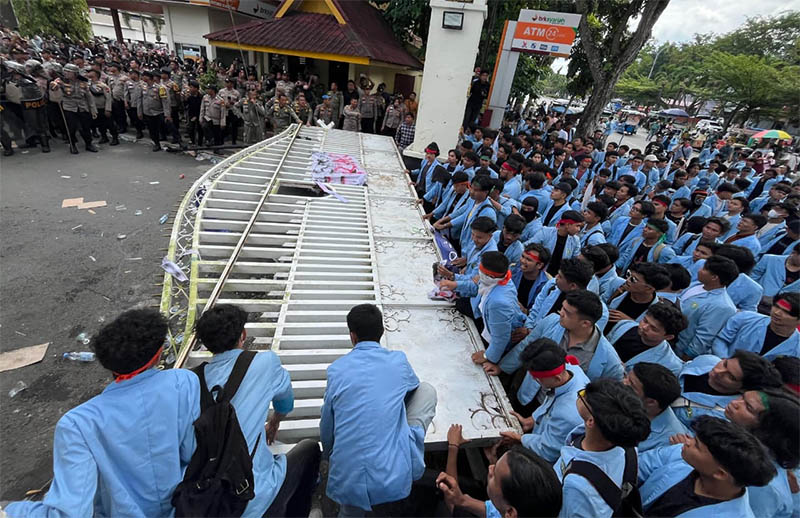 Ratusan Mahasiswa dari Badan Eksekutif Mahasiswa (BEM) Unri merubuhkan pagar saat aksi unjuk rasa di Gerbang Kantor Gubernur Riau, Kamis (14/8/2025).