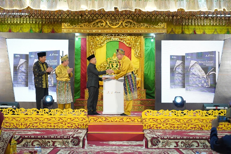 Dirut PHR Ruby Mulyawan menyerahkan Buku Melayu Lestari kepada Gubernur Riau Abdul Wahid di Balai Adat LAMR, Jumat (15/8/2025) malam.