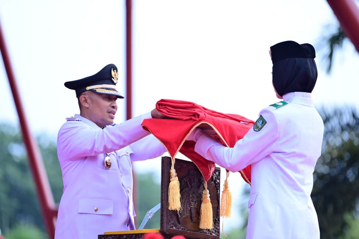 Anggota Paskibraka menyerahkan bendera merah putih kepada Wabup Bengkalis Bagus Santoso dalam acara penutunan bendera peringatan HUT RI ke 80 di Lapangan Tugu Bengkalis, Ahad (17/8/2025) sore.