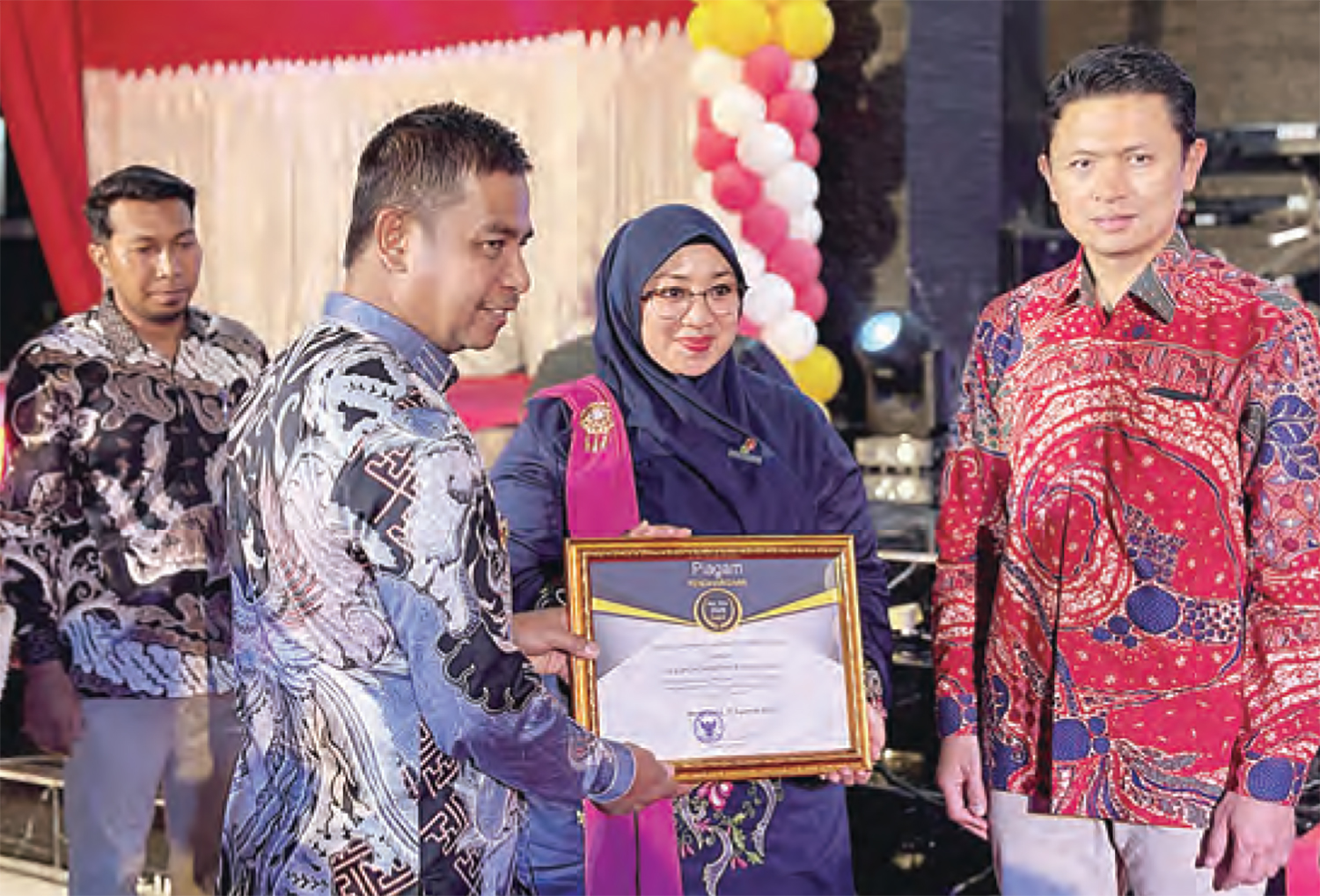 Bupati Kampar Ahmad Yuzar SSos MT menyerahkan piagam penghargaan Program CSR kepada Analis Dept FORKOM Vallerina didampingi Area Manager KKKS EMP Bentu Yoyok S Purwanto, Ahad (17/8/2025).