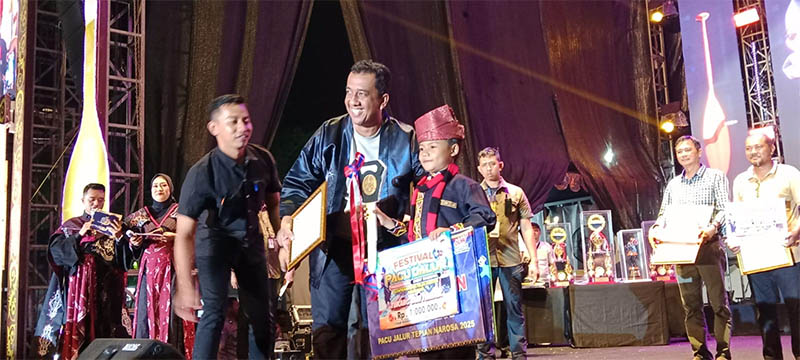 Kadis Pariwisata Riau, Roni Rakhmad menyerahkan penghargaan dan hadiah pada anak Tari Togak Luan pacu jalur tradisional tahun 2025 yang diraih Dapi Fadillah, dari Jalur Alam Cahayo Tuah Nagori