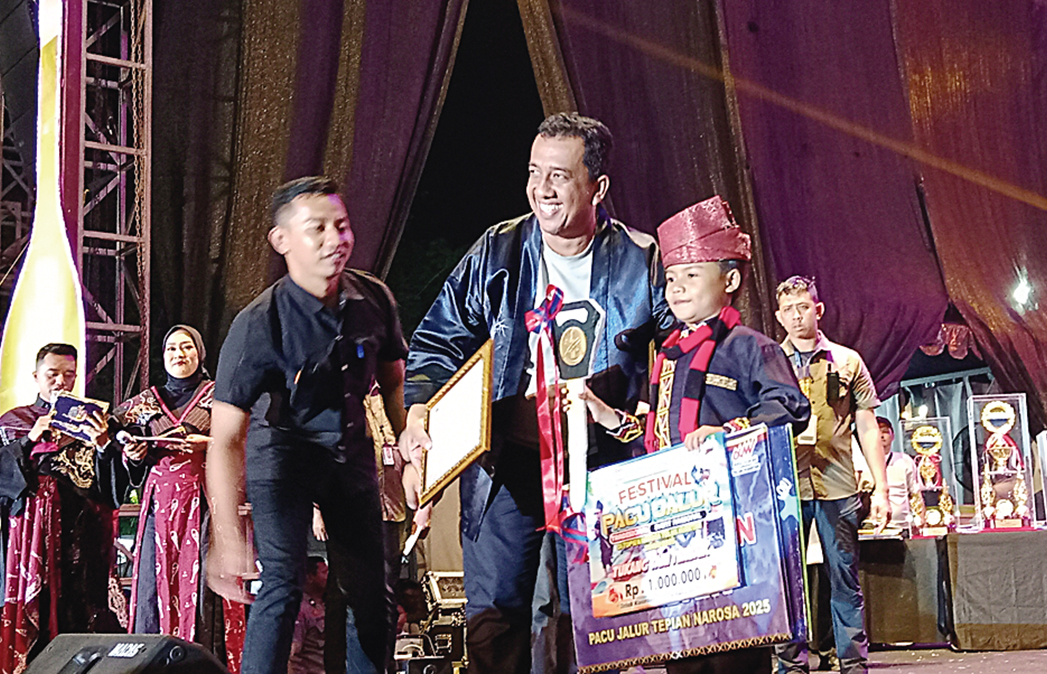 Dapi Fadhillah saat menerima hadiah Togak Luan Terbaik Pacu Jalur 2025 secara simbolis yang diserahkan Kepala Dinas Pariwisata Riau Roni Rakhmat pada malam penutupan di Taman Jalur, Telukkuantan, Ahad (24/8/2025).
