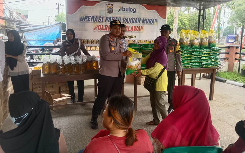 Kapolsek Pangkalan Kerinci AKP Rizkyan Tatit Hanafi SIK menyerahkan beras murah kepada masyarakat saat Operasi Pangan Murah di halaman Polsek Pangkalan Kerinci, Selasa (9/9/2025).