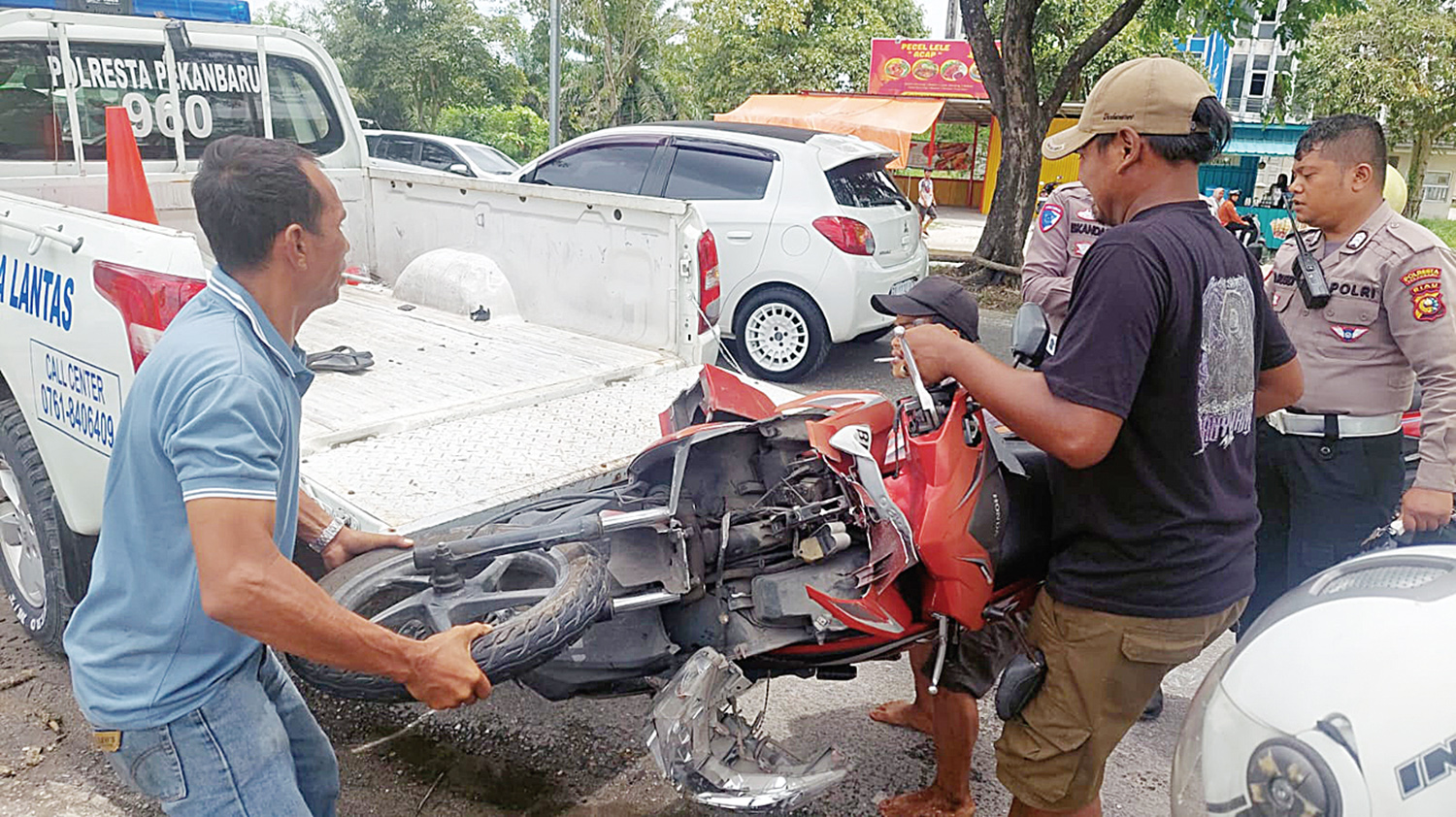 Petugas kepolisian dibantu warga mengevakuasi sepeda motor yang terlibat kecelakaan maut di Jalan Soekarno Hatta, Pekanbaru, Ahad (7/9/2025).