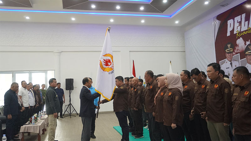 Wakil Ketua KONI Riau, M Yunus menyerahkan bendera KONI pada Ketua KONI Kuansing, Andi Cahyadi saat pelantikan disaksikan Bupati H Suhardiman Amby, Rabu (17/9/2025).