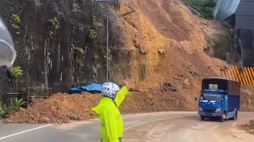 Petugas kepolisian mengatur lalu lintas kendaraan di titik longsor di Flyover Kelok 9, Limapuluh Kota, Sumbar yang sudah bisa dilewati, Jumat (19/9/2025) pagi.