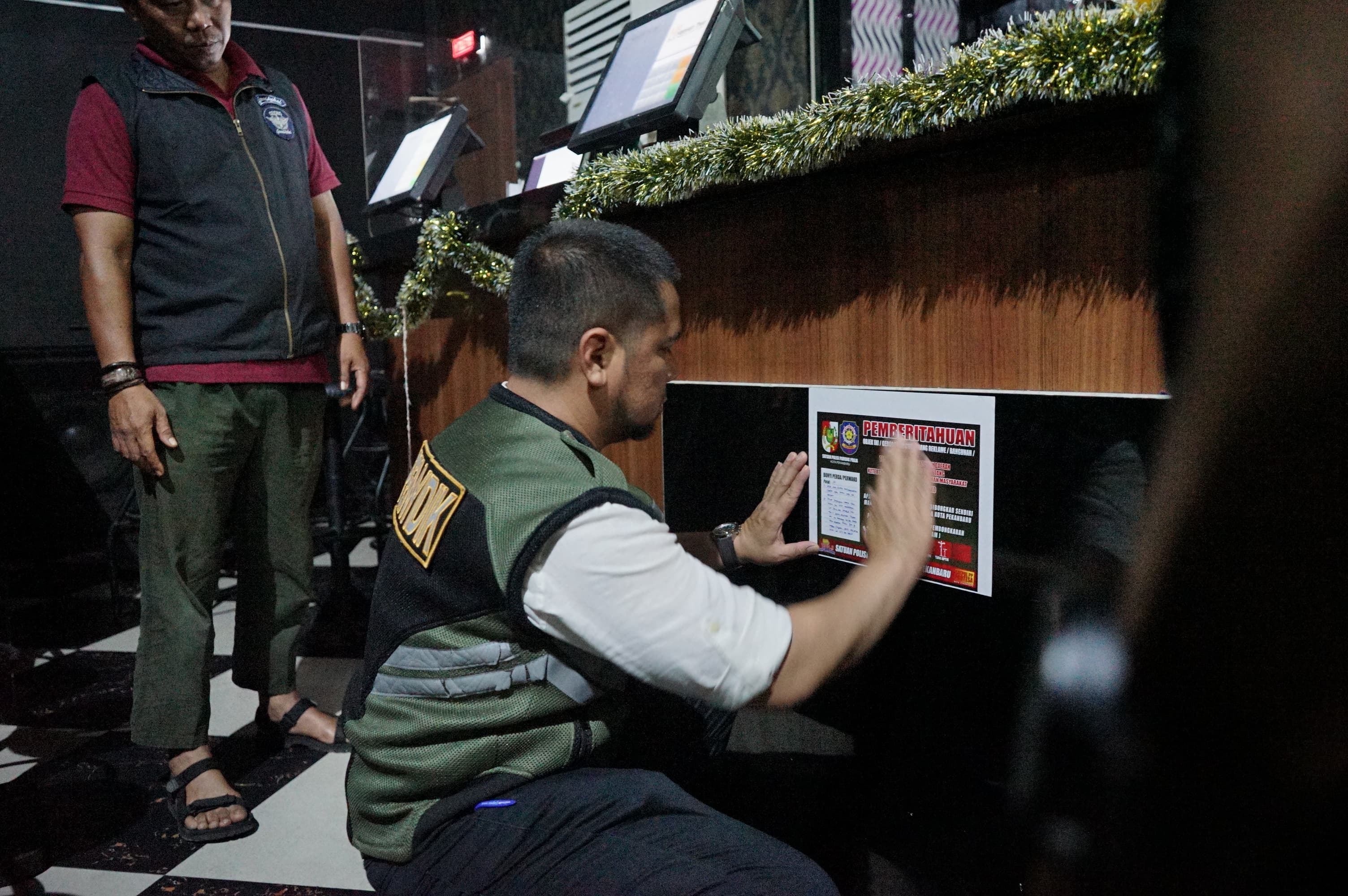 Petugas dari Satpol PP Kota Pekanbaru memasang pemberitahuan terhadap fasilitas H2 Panam yang masih belum memiliki izin di Jalan Subrantas Pekanbaru, Ahad (28/9/2025).