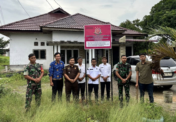 Tim Penyidik Kejari Rohul memasang plang penyitaan tanah dan bangunan rumah milik salah satu tersangka di Kecamatan Ujung Batu, Rabu (1/10/2025).