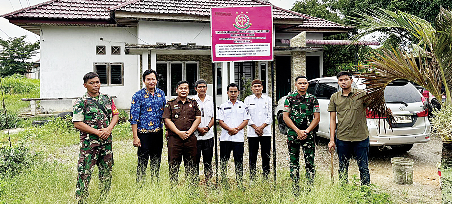 FOTO BERSAMA: Tim penyidik Kejari Rohul bersama TNI dan sejumlah saksi foto bersama usai memasang plang penyitaan tanah dan bangunan rumah milik tersangka Leni Aswita di Kecamatan Ujungbatu, Rabu (1/10/2025).