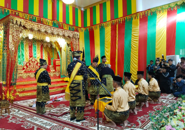 Prosesi pemasangan selempang saat penabalan gelar adat untuk Bupati sebagai Datuk Seri Setia Amanah dan Wabup Jhony Charles sebagai Datuk Seri Timbalan Setia Amanah, di Balai Adat LAMR Rohil.