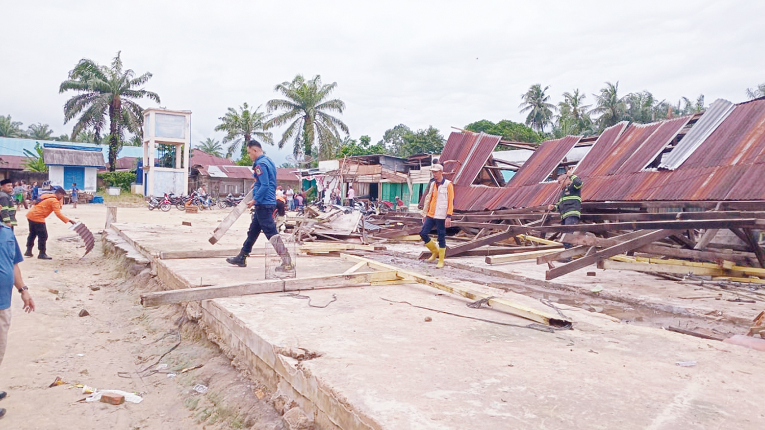 Personel BPBD Siak dan warga membersihkan puing pasar yang rubuh, dampak dari angin puting beliung di Kampung Sialang Sakti, Kecamatan Dayun, Kabupaten Siak, Ahad (5/10/2025).